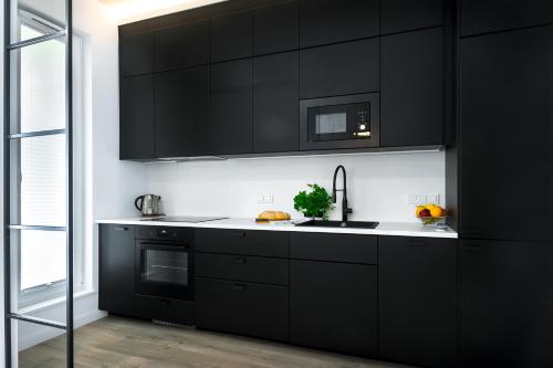 华沙Apartament Voila的厨房配有黑色橱柜和水槽