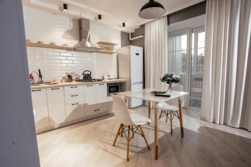乌拉尔斯克LUX 6 МКР дизайнерская комфортная студия с панорамными дверьми и большой лоджией的带白色桌椅的厨房以及带白色家电的厨房。