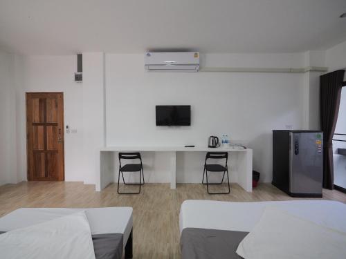 曼谷Prukpibul Apartment的一间卧室配有两张床和一张书桌及电视