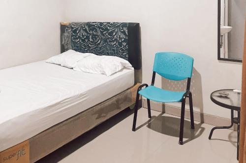 安汶Almira Homestay Ambon Mitra RedDoorz的一张床上,一张蓝色椅子放在房间里