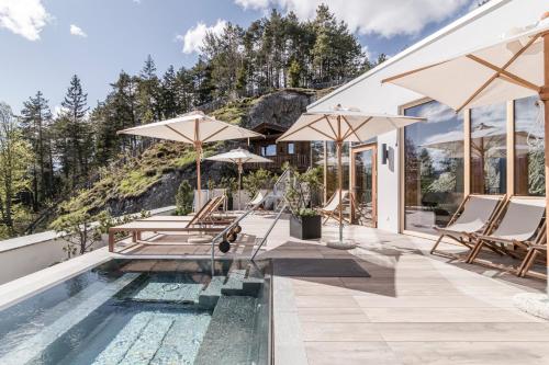 蒂罗尔-泽费尔德NIDUM- 休闲豪华酒店的房屋旁的游泳池配有椅子和遮阳伞