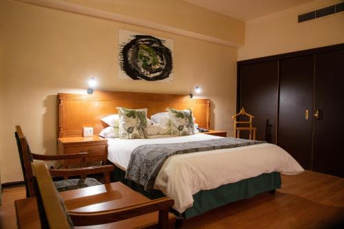 布隆方丹布隆方丹中央好酒店的一间卧室配有一张大床和一张桌子及椅子