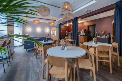 哥本哈根Motel One Copenhagen的一间设有白色桌椅的餐厅和一间酒吧
