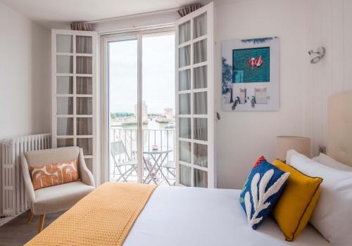 拉罗谢尔Tour de Nesle La Rochelle Vieux Port 3 etoiles的一间带一张床和一把椅子的卧室以及一个阳台