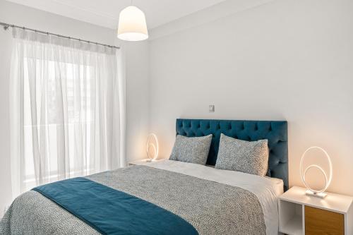 雅典BillyMare central Glyfada apartment的白色卧室设有蓝色的床和窗户