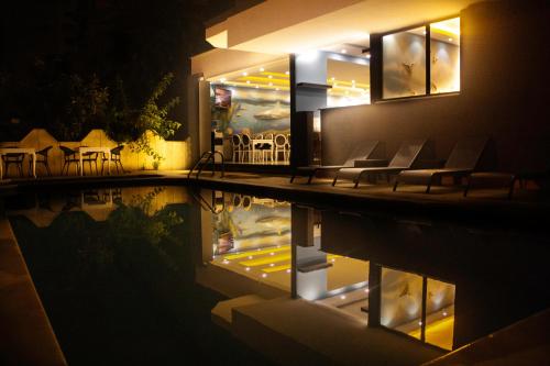 阿拉尼亚Livaneli Boutique Otel的一座带椅子的建筑和一座夜间游泳池