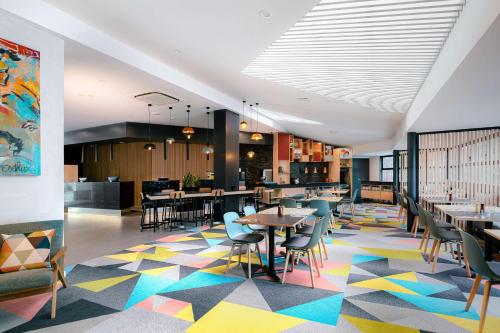 惠灵顿Atura Wellington的一间设有桌椅的餐厅,位于色彩缤纷的楼层