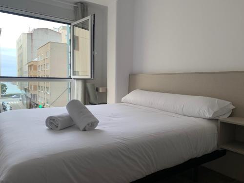 拉科鲁尼亚Oxford Suites Ciudad de la Coruña的卧室配有白色的床和2条毛巾
