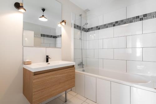阿罗芒什莱班Maison avec beau jardin - Centre ville d'Arromanches的白色的浴室设有水槽、浴缸和浴缸,并带有投影仪。