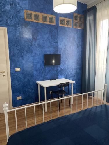 卡斯特拉玛雷帝斯达比亚B&B Acqua Azzurra的一间设有桌子的房间和蓝色墙壁上的电视