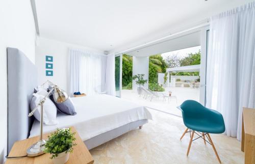 蓬塔卡纳Luxury 5-room modern villa with movie theater at exclusive Punta Cana golf and beach resort的白色卧室配有床和蓝椅