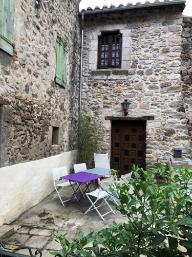 孔夫朗自由城Les Maisons du Conflent, maisons familiales en pierre au coeur des remparts的大楼前的紫色桌子和椅子