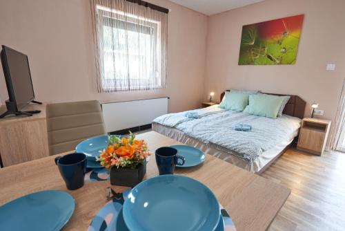 加尔多尼Thermal Apartman - FSZ的一间卧室配有床、两张桌子和一台电视