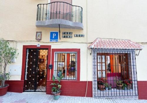 阿尔姆尼卡Pension casa Fina Ruiz的一间商店,拥有一座红色和白色的建筑,设有阳台