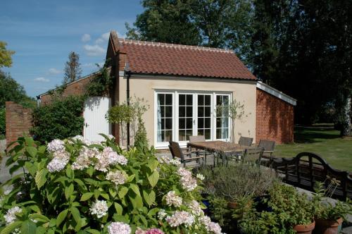 East HarlingField Cottage Bed and Continental Breakfast的一座小房子,配有桌椅和鲜花