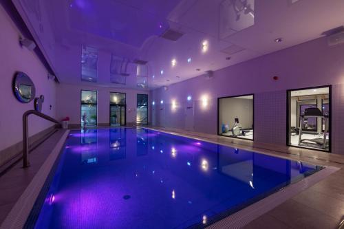 格丁尼亚安塔尔斯酒店的一座紫色照明建筑中的大型游泳池