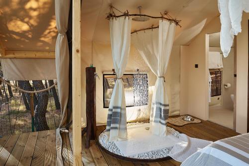 波尔Abeille Maison Glamping Resort Zlatni Rat -Adults Only的一间卧室配有带窗帘的床和窗户