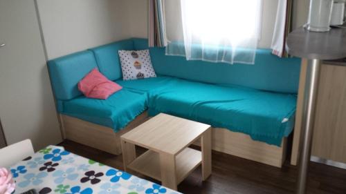 劳恩尼克MOBILHOMES baie PERROS -GUIREC-LOUANNEC的一张蓝色的沙发,位于一个小房间里,配有桌子