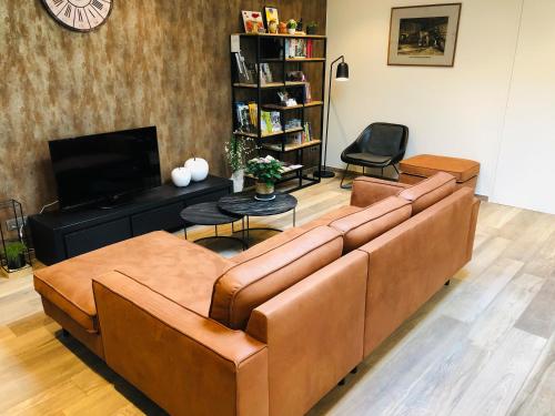 波佩林赫蒂霍美尔贝尔勒酒店的客厅配有棕色沙发和电视