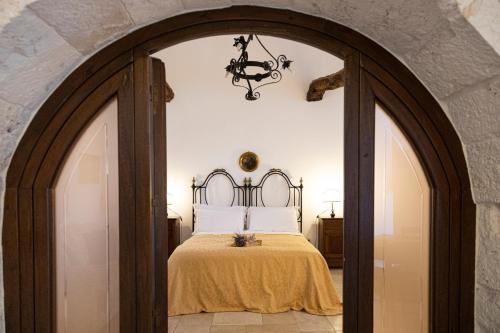 CrispianoMasseria Pilano的拱门通往卧室,卧室配有床