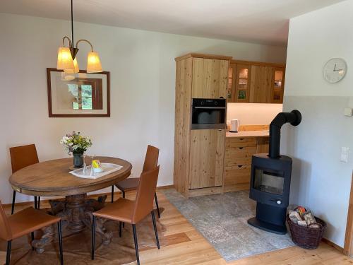 ArriachKlösterle Haus Egon的厨房以及带桌子和燃木炉的用餐室。