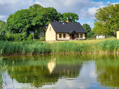 BarwicePRZYSTANEK nowEKOprzywno - Żółty Domek Pod Kasztanem的湖畔黑屋顶的房子