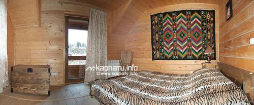 米库利钦У Тарнавских的木制客房内的一间卧室配有一张大床