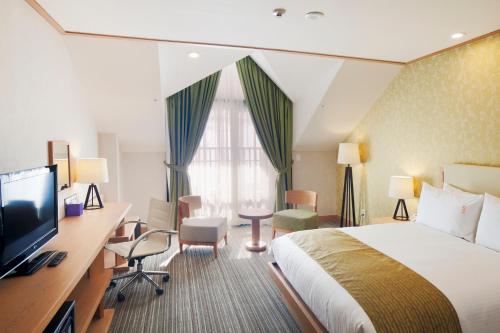 平昌平昌阿尔卑希亚假日酒店的酒店客房配有一张床、一张书桌和一台电视。
