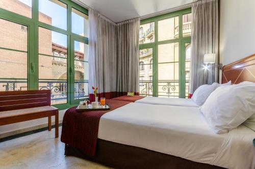 巴塞罗那EXE莱塔纳皇宫酒店的一间卧室设有一张大床和大窗户