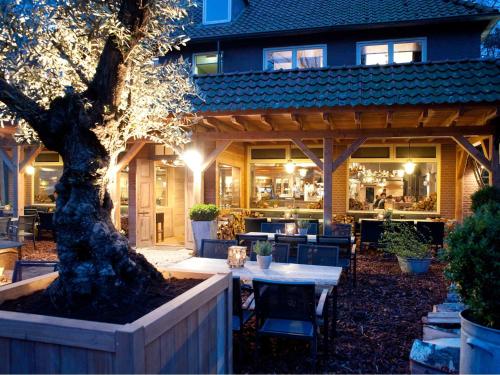 奥斯特韦克艾克先生酒店及餐厅的一座建筑前的庭院,庭院里设有桌子和一棵树