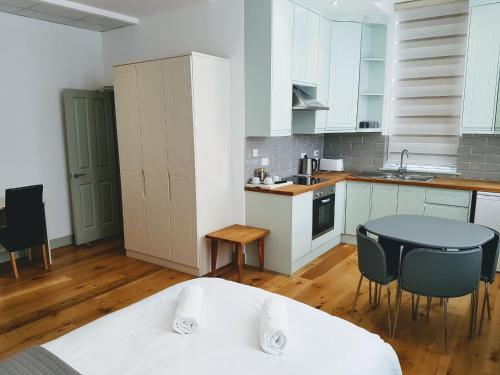 伦敦Forest House Hotel的厨房配有白色橱柜和桌椅