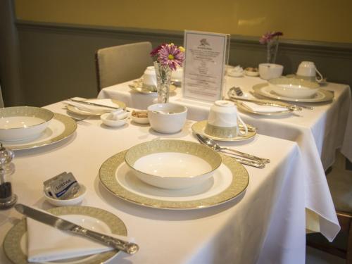 伊斯特布恩Albert & Victoria Guest House的一张桌子上放着白板和银器