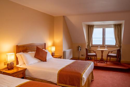 恩尼斯克朗Waterfront House & Restaurant的酒店客房设有两张床、一张桌子和一个窗户。