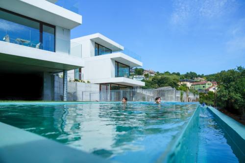 坎加斯德穆拉索Acíes Apartamentos Turísticos的两个孩子在房子旁边的游泳池游泳