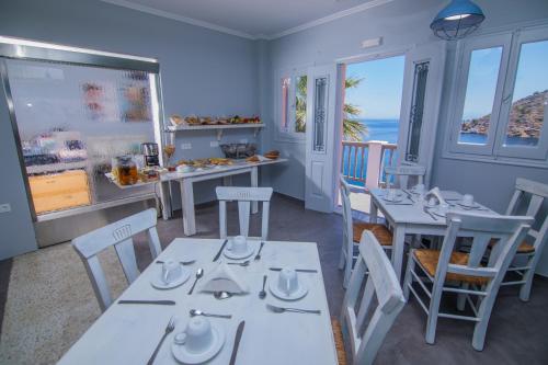 锡米Niriides Hotel Apartments的一间配备有白色桌椅的海景餐厅