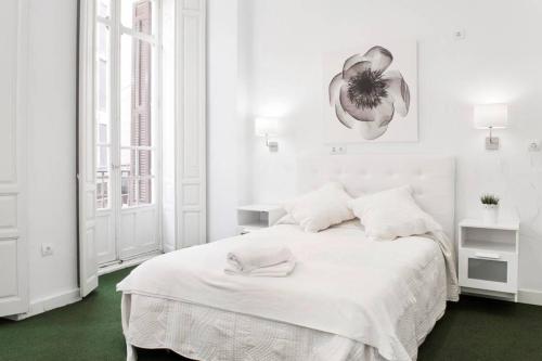 马拉加Company 34的白色的卧室,配有白色的床,墙上挂着花朵