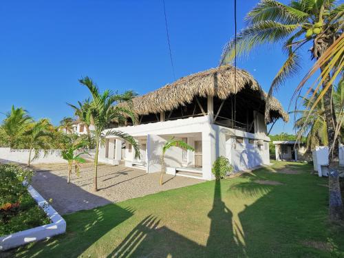 科韦尼亚斯Casa el Muelle的一座带茅草屋顶的建筑和一座种植了棕榈树的庭院
