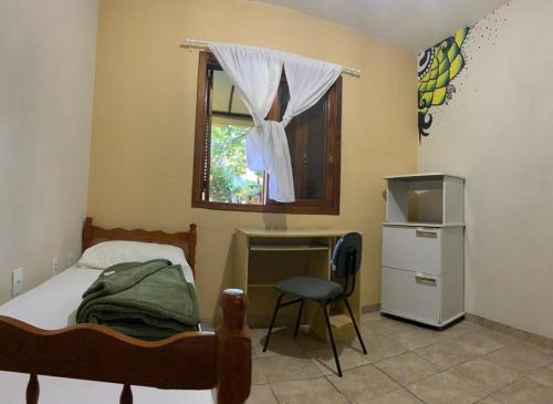 阿雷格里港Pousada Agronomia的一间卧室配有一张床、一张书桌和一个窗户。