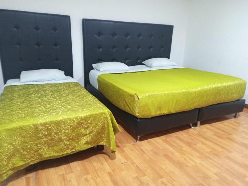 波哥大Embassy On Holidays的客房内的两张床和绿色床单