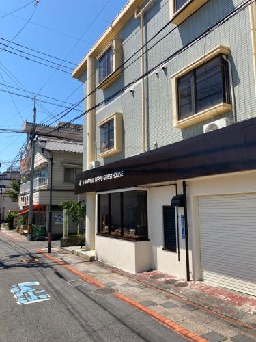 别府J-Hoppers Beppu Guesthouse ジェイホッパーズ別府ゲストハウス的街道边的建筑物