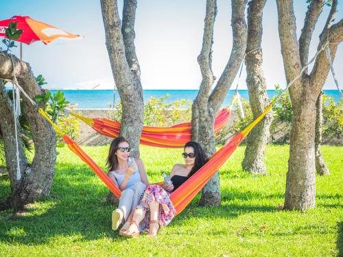 石垣岛ザ・ビーチテラスホテルアオ石垣的两个女人坐在草地上的吊床上