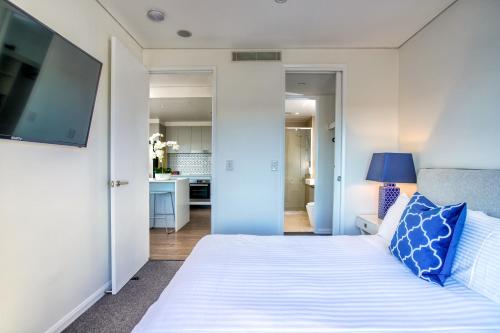 土乌巴Inspire Boutique Apartments的卧室配有带蓝色枕头的大型白色床