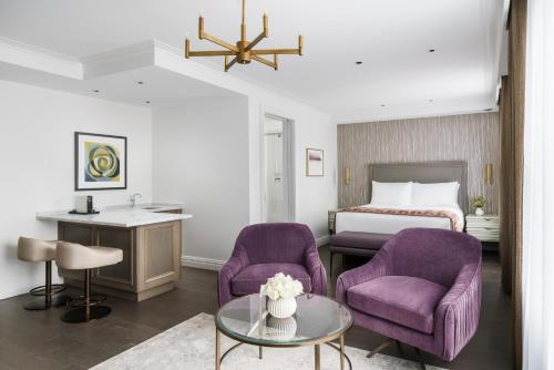 纽约The Wallace Hotel的酒店客房设有两张紫色椅子和一张床