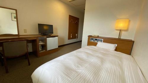 名张Smile Hotel Nabari的酒店客房配有一张床、一张书桌和一台电视。
