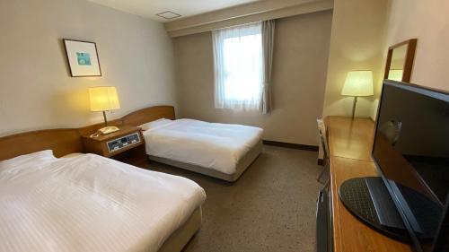 名张Smile Hotel Nabari的酒店客房设有两张床和一台平面电视。