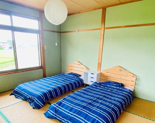 壹岐市ikibase Guest House的两张睡床彼此相邻,位于一个房间里
