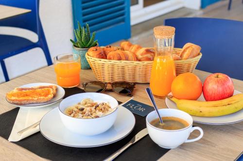 圣弗洛朗Hôtel Flor的餐桌上放着盘子和一篮水果