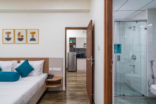 海得拉巴SKYLA Serviced Apartments & Suites, Hi-Tech City的一间卧室设有一张床和一个玻璃淋浴间