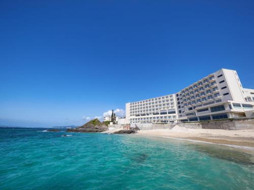 恩纳Hotel Miyuki Beach的海滩上的酒店,靠近一片水域