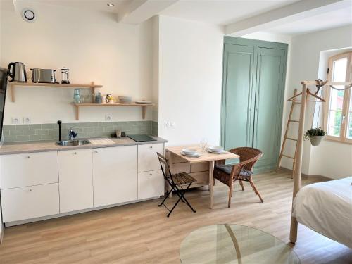 洛尔格Carnets de voyage Coté studios的厨房配有白色橱柜、桌子和书桌。